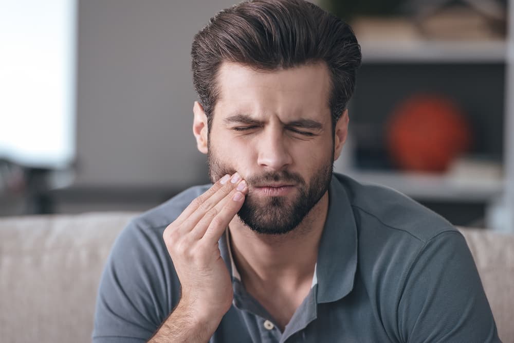 man holding his cheek from a toothache